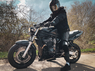 motorcyclist dressed in black sits on his black motorcycle