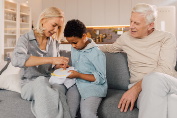 Obraz premium Boy asking his grandmother while she doing needlework at home