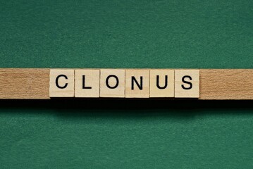 gray word clonus made of wooden square letters on green background