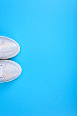 Fototapeta na wymiar Silver sneakers on a blue background with place for text