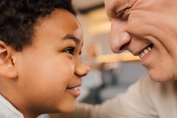 Boy looking at the eyes of his grandfather while spending time with him at home