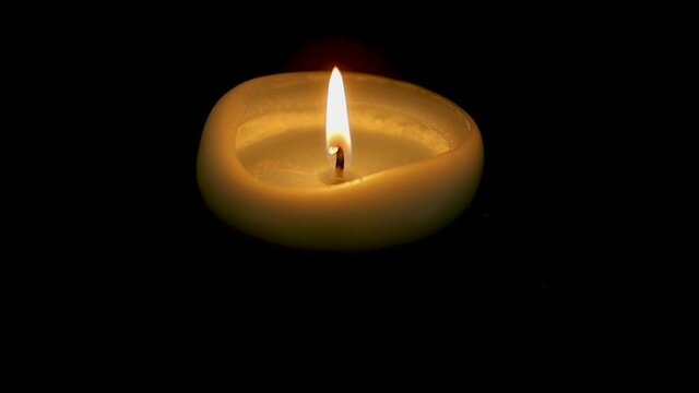 bougie allum&eacute;e dans le noir avec la flamme qui vacille