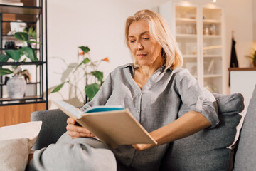 Female sitting at sofa with book at her hands