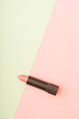 Pink lipstick in a combination of pastel pink and green background. Makeup cosmetic beauty care concept. Flat lay photography with copy space.