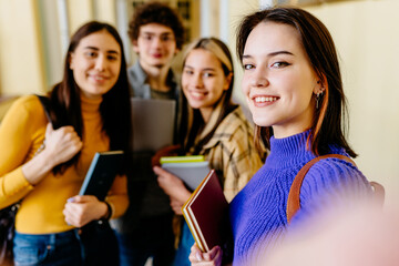 Education, high school, technology and people concept. Group of four smiling students with smart phone taking photo or video indoors.