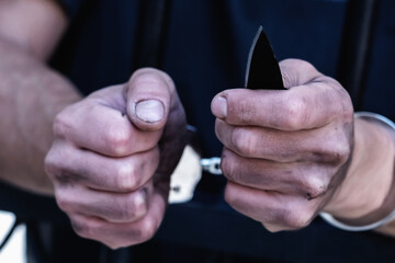 Fototapeta premium Close up handcuffed man with a knife imprisoned for crime, punished for serious villainy. Arrest, gangster, pain concept. Selective focus.