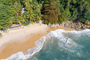 Aerial view of sunny tropical beach with turquoise waves crashing on white sand. Praia do Éden...