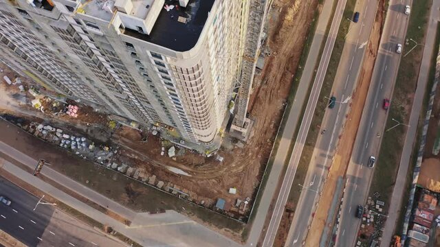 Aerial top down view construction with yellow tower crane working on building site. Flight over constructions development. Concept of construction industry, heavy machinery and workers employed