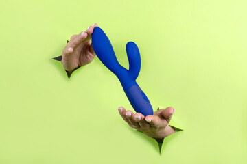 A Erotic toy for pleasure in the hands of a woman on a green background. A device for masturbating...