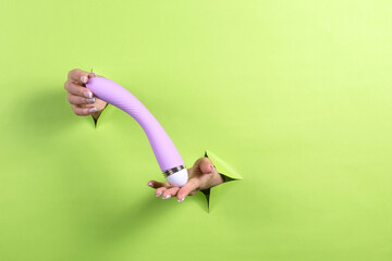 A Erotic toy for pleasure in the hands of a woman on a green background. A masturbation device for...
