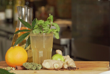 Healthy drink made of lime, ginger, and cannabis on a wooden surface - obrazy, fototapety, plakaty