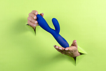 A Erotic toy for pleasure in the hands of a woman on a green background. A device for masturbating...