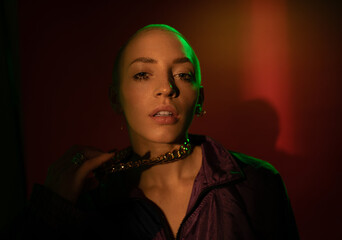 Woman standing at the dim light and posing to the camera while holding her chain