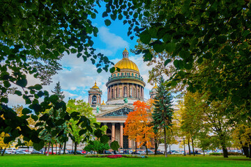 Isaac's Cathedral in Saint Petersburg. Russia in autumn day. Museum in the center of St. Petersburg. St. Isaac's Square on background blue sky. Isaac's Cathedral in crowns of trees. Cities of Russia