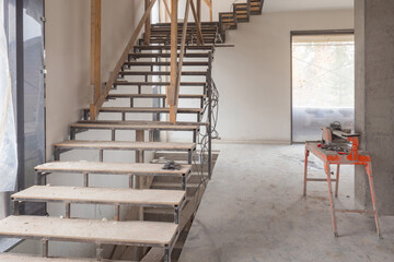 Renovated room with a stairs. Freshly built building from inside. Premises under construction are ready for finishing work. Stairs lead to second floor. Concept - services for finishing house.