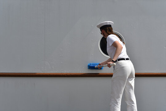 girl military sailor cadet washes the keel of the ship with a brush