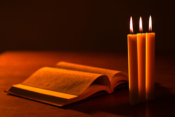 Church candles next to book. Table with bible and candles close-up. Light the Bible with...