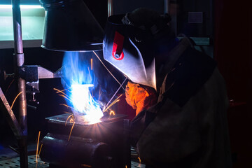 Welder during work. The man does hot welding. Hot welding of metal parts. A welder in a protective mask is working. Career as a welder. Connection of metal parts. Concept - sale of welding equipment