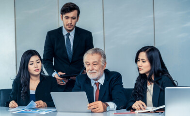 Senior caucasian manager working in office with assistance of young Asian business people and...