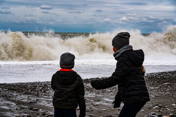 children look at the white waves at the sea