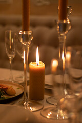 Romantic candlelight dinner in a beautiful restaurant. Natural wax candles on the table. Lighted candles and glasses of wine on the table in the darkness.