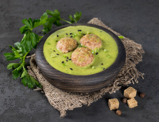 Cream soup green radish potato with meatballs, parsley, croutons  in a wooden bowl on a dark gray background in rustic style