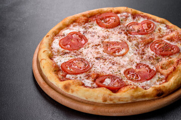 Tasty fresh oven pizza with tomatoes, cheese and basil on a concrete background