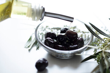 olive oil and olives over white table