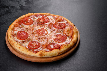 Tasty fresh oven pizza with tomatoes, cheese and basil on a concrete background