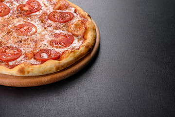 Tasty fresh oven pizza with tomatoes, cheese and basil on a concrete background