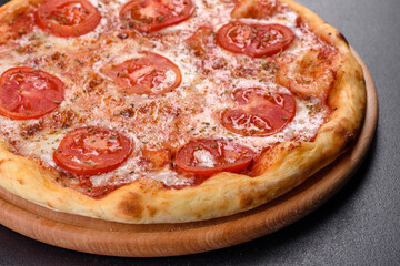 Tasty fresh oven pizza with tomatoes, cheese and basil on a concrete background