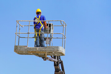Electrician in the cart. Worker in a safety helmet and safety equipment in a lifting trolley