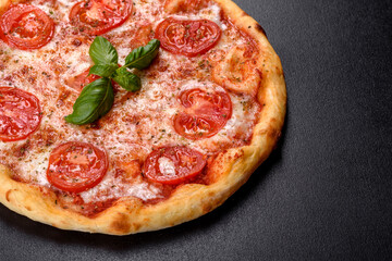 Tasty fresh oven pizza with tomatoes, cheese and basil on a concrete background