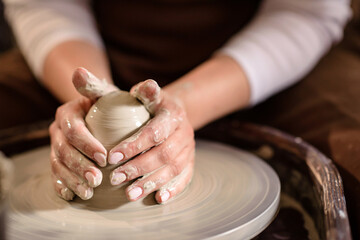Hands of a woman potter close-up with selective focus.