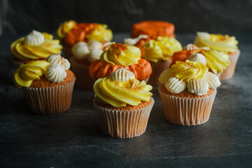 Delicious muffins. Orange and lemon cream muffins. Cupcakes on a concrete table 