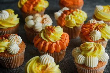 Delicious muffins. Orange and lemon cream muffins. Cupcakes on a concrete table 