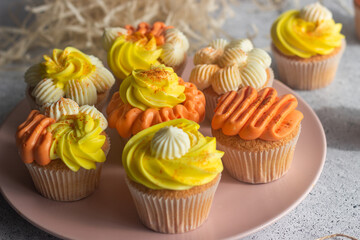 Delicious muffins. Orange and lemon cream muffins. Cupcakes on a concrete table 