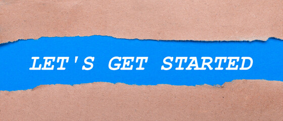 A strip of blue paper with the words LET IS GET STARTED between the brown paper. View from above