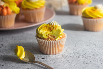 Delicious muffins. Orange and lemon cream muffins. Cupcakes on a concrete table 