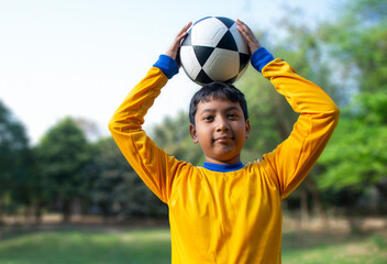 Portrait of boy holding soccer ball on head	