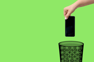 The mobile phone is thrown into the trash can. The concept of technology obsolescence and recycling...