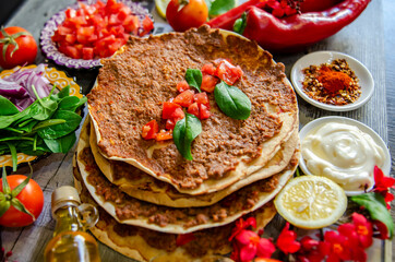 Lahmacun is a round, thin piece of dough topped with minced meat, minced vegetables, and herbs including onions, garlic, tomatoes, red peppers, parsley, spices such as chili pepper, paprika, cinnamon.