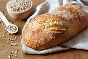 Bochenek chleba i ziarna pszenicy w drewnianej misce