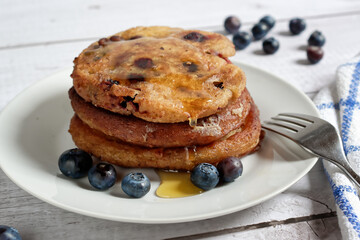 A stack of homemade pancakes with blueberries, drizzled with honey.