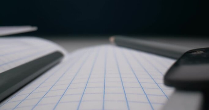 detailed extreme close-up checkered notebook with pencils and compasses.