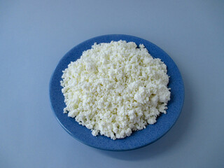 Blue plate with cottage cheese on a light blue background in the middle. View from above. Isolated. 