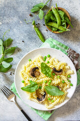 Healthy eating. Pasta fusilli with mushrooms, spinach and green peas on stone table. Vegetarian vegetable mushrooms pasta. Diet menu. Top view flat lay. Copy space.