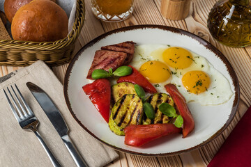 Fried sausage with fried eggs and pepper and zucchini on a rustic background