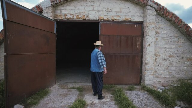 World economic crisis. Desperate farmer near an empty barn. The man went bankrupt due to the crisis. A ruined ranch without cows, pigs, sheep, animals. Empty stable, storage. Unemployed farmer.