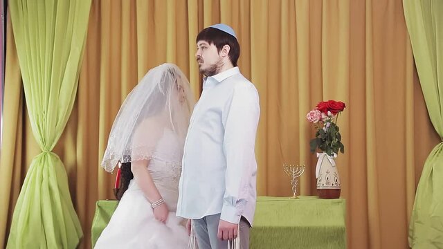 During the chuppah ceremony, the Jewish bride and groom in the synagogue, the bride walks around the groom seven times. Medium plan